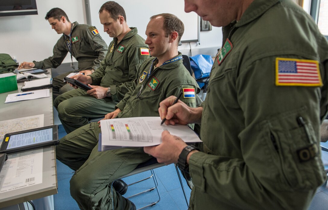 (Archive Photo) Aircrew from four countries take part in a mission brief before takeoff from Pápa Air Base, Hungary, March 23. The Strategic Airlift Capability program, a multinational mission, is comprised of 12 countries operating out of Pápa Air Base. The international unit is called the Heavy Airlift Wing, and is the first non-NATO unit of its kind. (U.S. Air Force Photo/Master Sgt. Brian Ferguson)