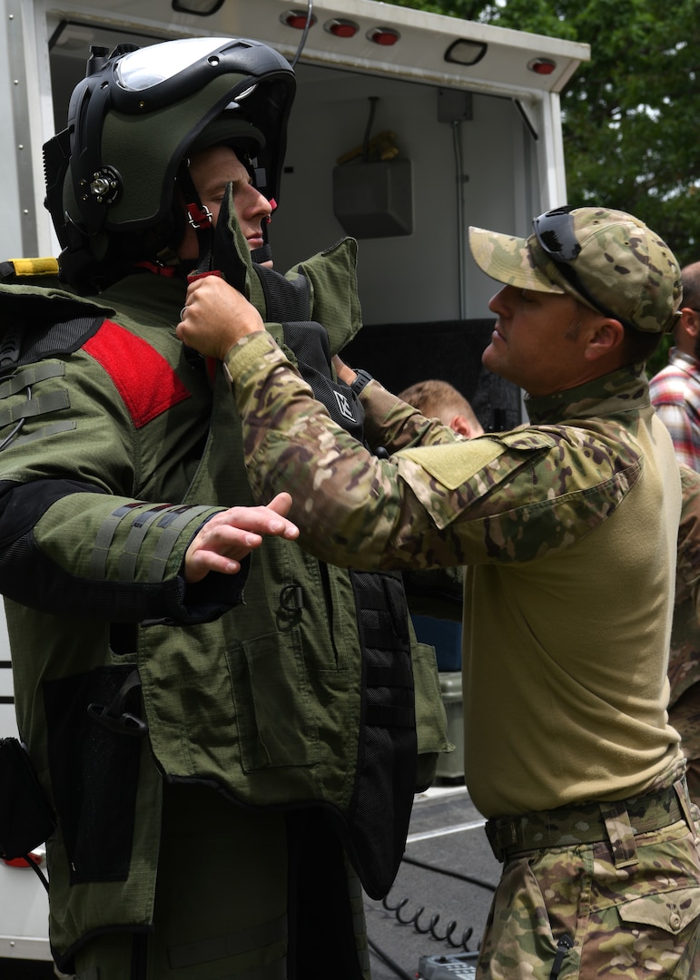 Staff Sgt. Jesse Poulsen, 142nd Civil Engineering Squadron Explosive Ordnance Disposal technician, helps Staff Sgt. Eric Franco, 104th CES EOD technician, put on a bomb suit before inspecting a car for a potential vehicle-borne improvised explosive device during Audacious Warrior 2019, June 21, 2019