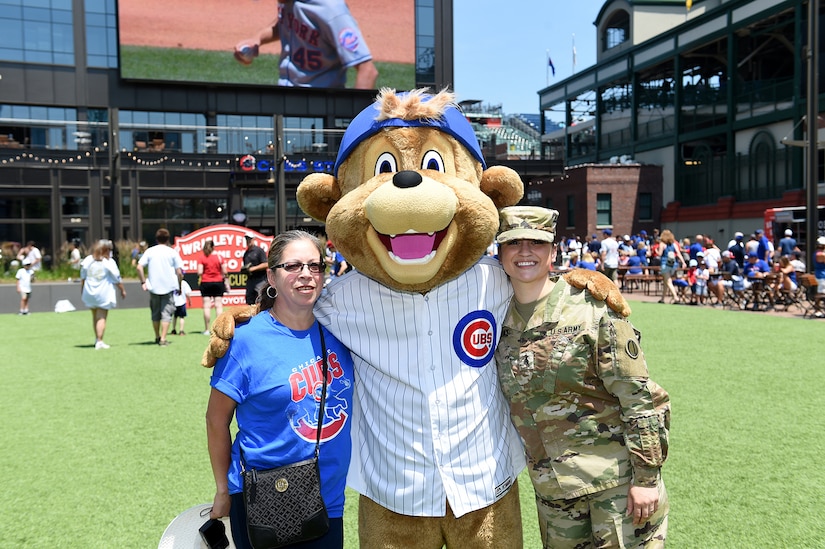 Sgt. Maribel Meraz, right, assigned to the 85th U.S. Army Reserve Support Command headquarters, pauses for a photo with her mother and Clark, Chicago Cubs mascot, at Gallagher Way, adjacent to the Chicago Cubs Wrigley Field, June 27, 2019, after reenlisting for a third six-years in the Army Reserve.