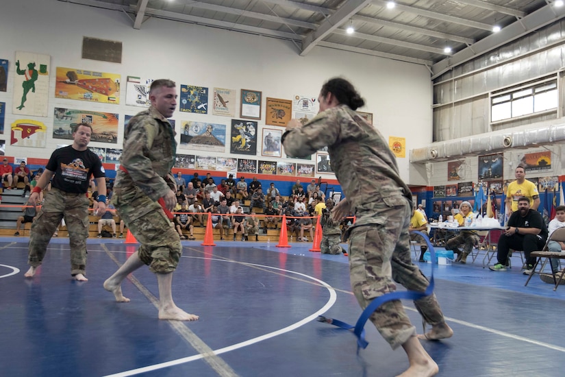 United States Army Sgt. Linsey Williams, right, a public affairs mass communications specialist assigned to the 34th Red Bull Infantry Division, Minnesota Army National Guard, maneuvers out of a hold by Army Capt. Joshua Harmon, a chaplain with 8th Battalion, 229th Aviation Regiment, during a combatives tournament at Camp Arifjan, Kuwait, June 23, 2019. U.S. Army Central promotes good unit moral which enhances unit cohesion and reinforces the importance of excellence.