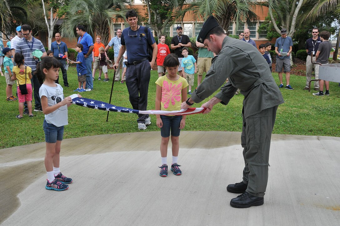 Naval Surface Warfare Center Panama City Division personnel demonstrate the proper U.S. flag folding technique during a family event.