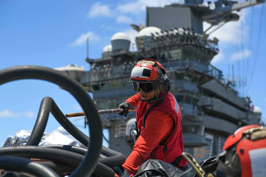 A sailor looks through equipment on a ship.