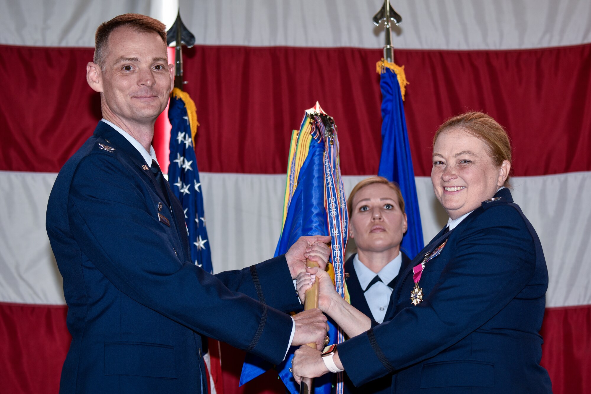 U.S. Air Force Col. Mary Stewart (right), outgoing 377th Medical Group commander, passes the guidon to Col. David Miller, 377th Air Base Wing commander in a change of command ceremony at Kirtland Air Force Base, N.M., June 27, 2019. Stewart leaves Team Kirtland to support Joint Base San Antonio-Lackland, Texas, as the 59th Medical Support Group commander. (U.S. Air Force photo by Airman 1st Class Austin J. Prisbrey)