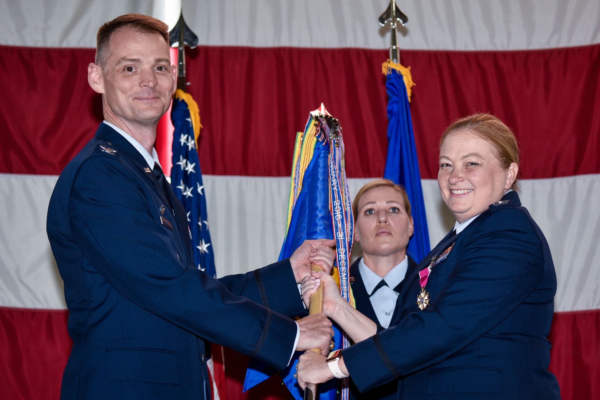 U.S. Air Force Col. Mary Stewart (right), outgoing 377th Medical Group commander, passes the guidon to Col. David Miller, 377th Air Base Wing commander in a change of command ceremony at Kirtland Air Force Base, N.M., June 27, 2019. Stewart leaves Team Kirtland to support Joint Base San Antonio-Lackland, Texas, as the 59th Medical Support Group commander. (U.S. Air Force photo by Airman 1st Class Austin J. Prisbrey)