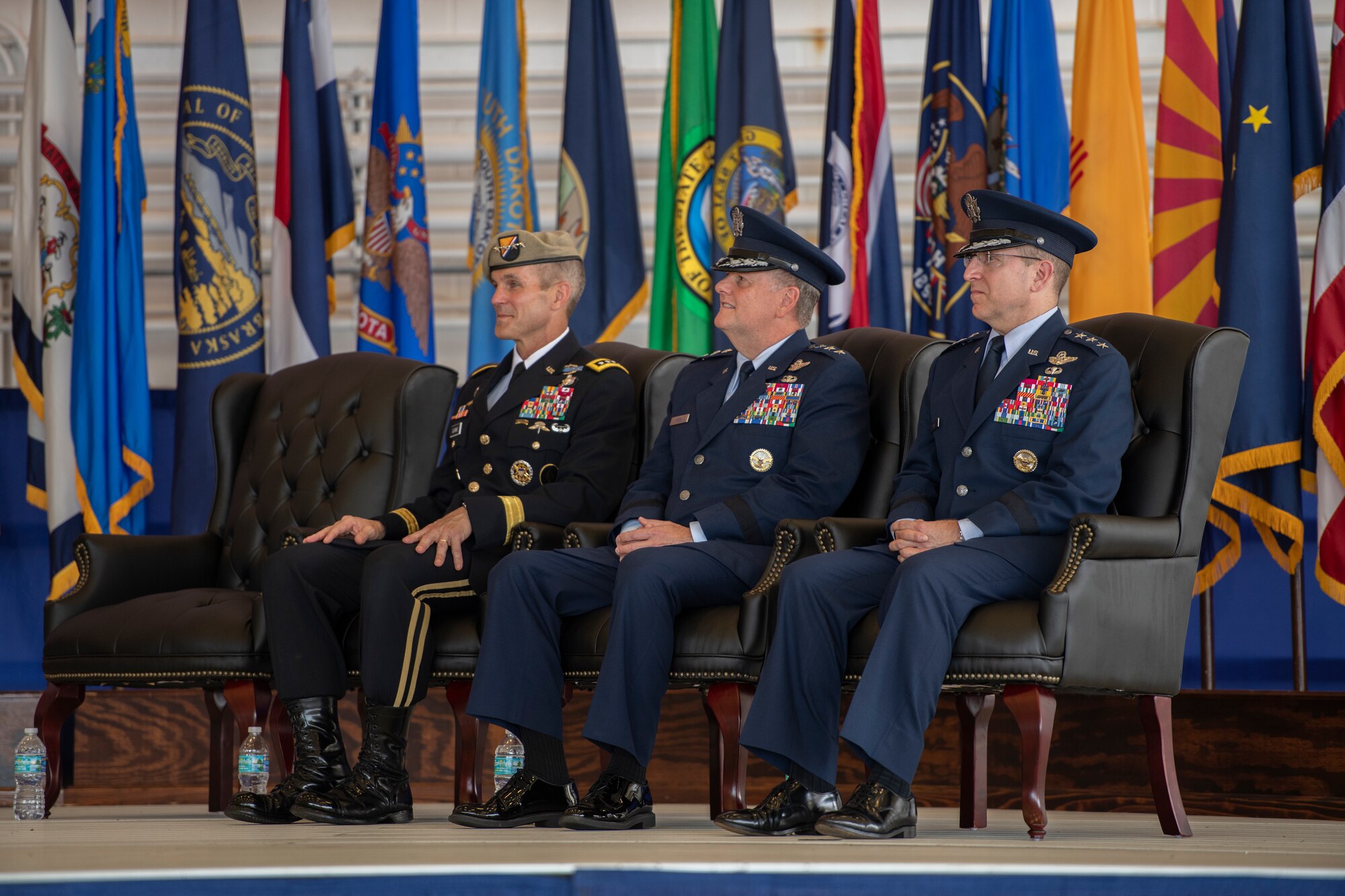 Three people sitting on a stage listening to a presentation.