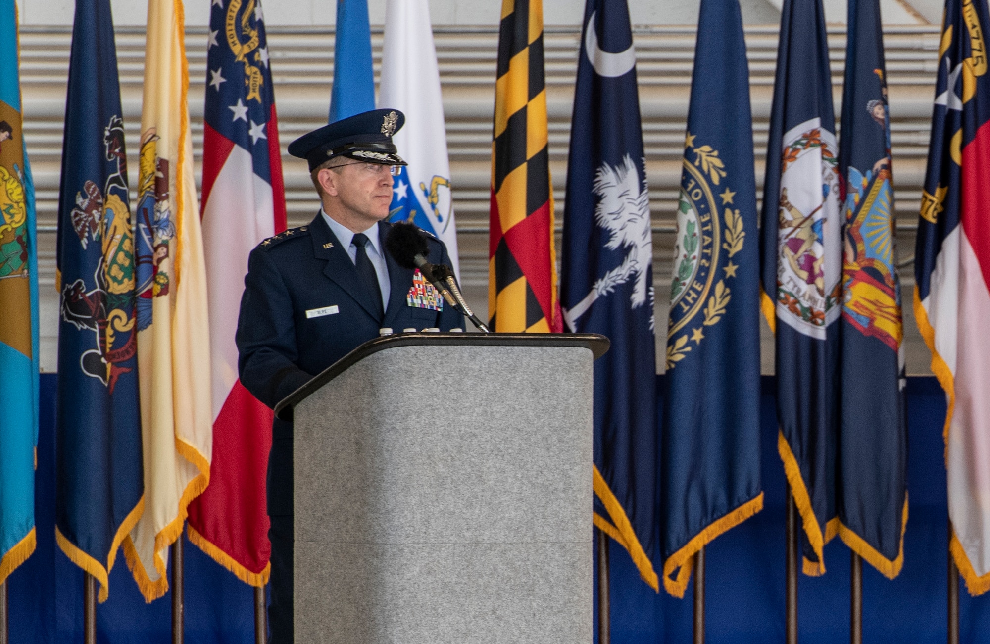 One person speaking in front of multiple flags.