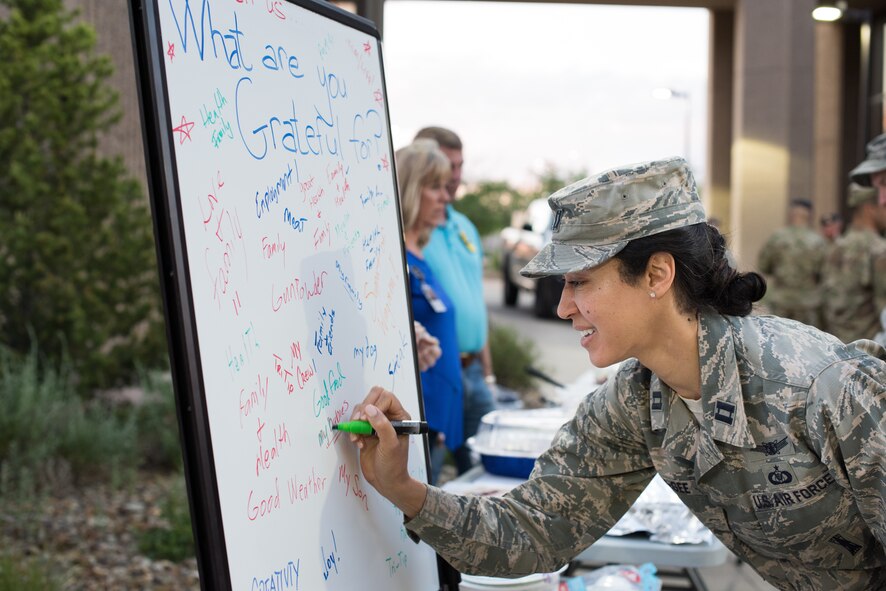 Capt. Yulonda McGee, National Reconnaissance Office Operations Squadron crew commander, writes what she is grateful for before enjoying her meal at the chaplain’s office hosted night operations resiliency picnic at Schriever Air Force Base, Colorado, June 26, 2019. Airmen were encouraged to write down what they were grateful for on a white board before enjoying their free meal which included tri-tip and various sides. (U.S. Air Force photo by 2nd Lt. Idalí Beltré Acevedo)