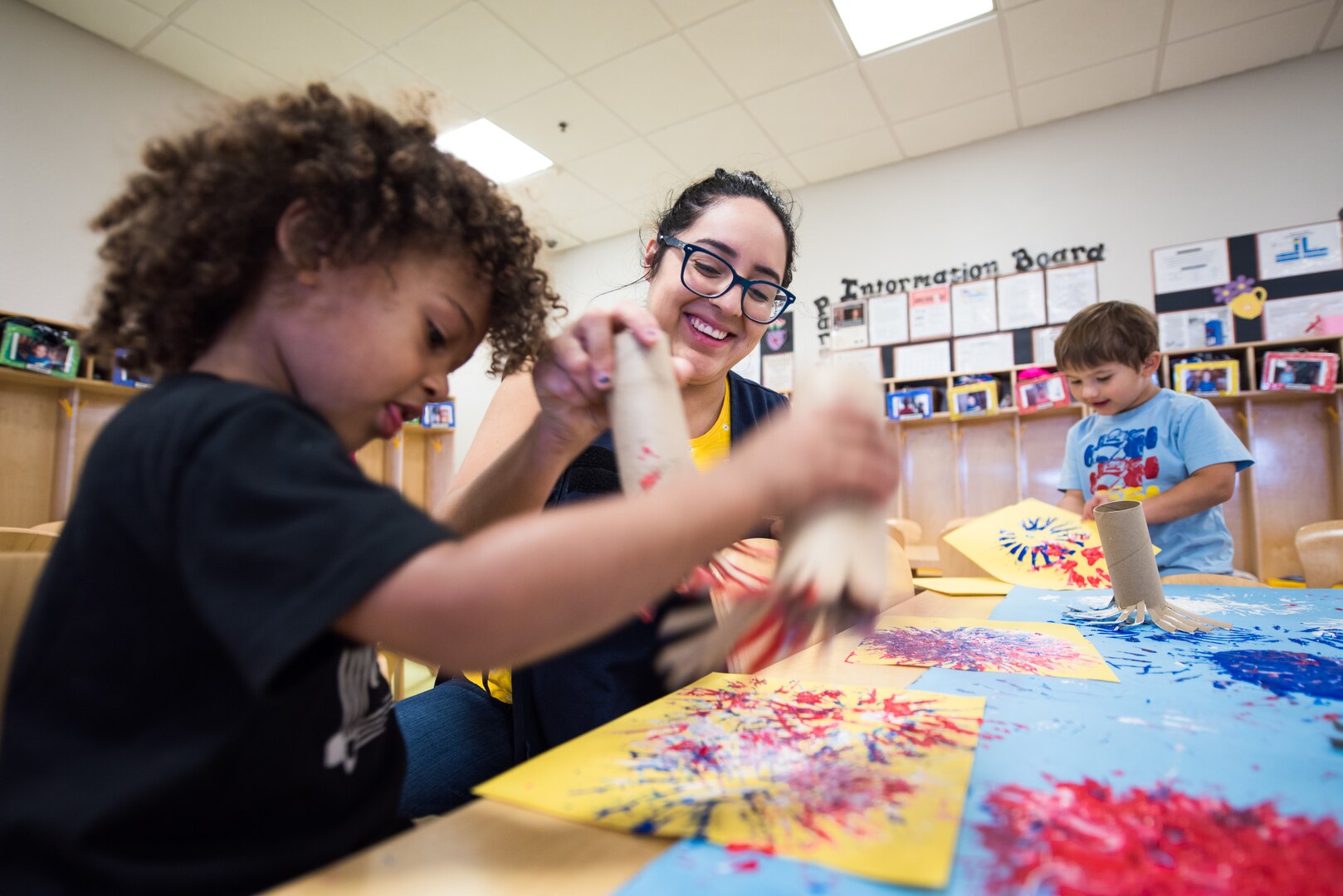 Stephanie Salazar, 502nd Force Support Squadron, child development program assistant, helps kids create a fire work painting, June 11, 2019, at the Gateway Child Development Center, Joint Base San Antonio-Lackland, Texas.