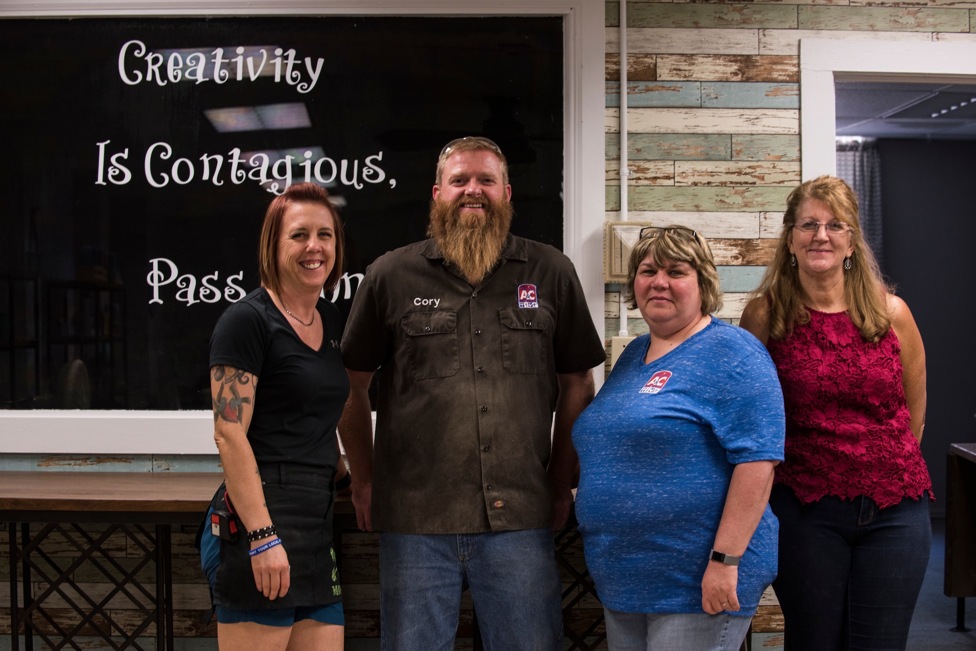 The 90th Force Support Squadron Arts and Crafts Center employees pose for a photo in front of their newly renovated craft wall with the quote “Creativity is contagious. Pass it on” by Albert Einstein June 27, 2018, on F.E. Warren Air Force Base, Wyo. The center is open Tuesday through Friday, 10 a.m. to 5 p.m. and welcomes anyone with base access to walk in and learn how they can best utilize the facility or place a custom order. (U.S. Air Force photo by Senior Airman Abbigayle Williams)