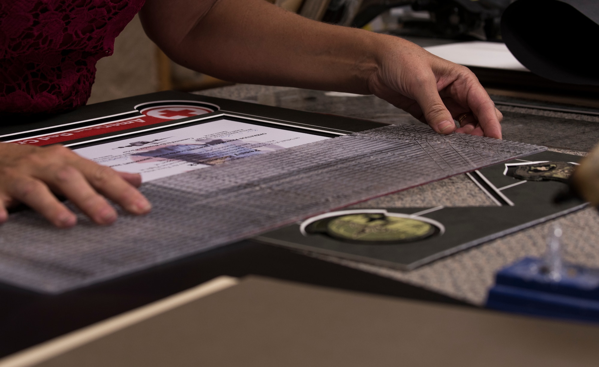 Tamra Windows, 90th Force Support Squadron Arts and Crafts Center employee, measures a framing mat before placing it into the custom built frame June 27, 2018, on F.E. Warren Air Force Base, Wyo. A few items that can be custom made in the shop are awards, shadow boxes and t-shirts. (U.S. Air Force photo by Senior Airman Abbigayle Williams)