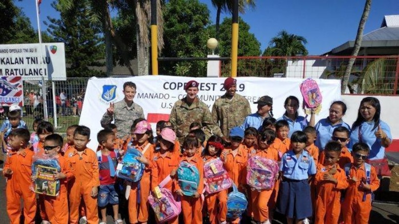 U.S. military members take a group photo with students from a local school during the Cope West 19 open house at Sam Ratulangi International Airport, Manado, Indonesia June 22, 2019.  During the event, a U.S. Indo-Pacific Command Team of U.S. Embassy-Jakarta members set up a small kiosk showcasing U.S.-Indonesian 70th anniversary bilateral relations items and educational handouts for children. The team handed out educational books, back packs, writing supply materials, in commemoration of diplomatic relations between the U.S. and Government of Indonesia. (Courtesy photo)