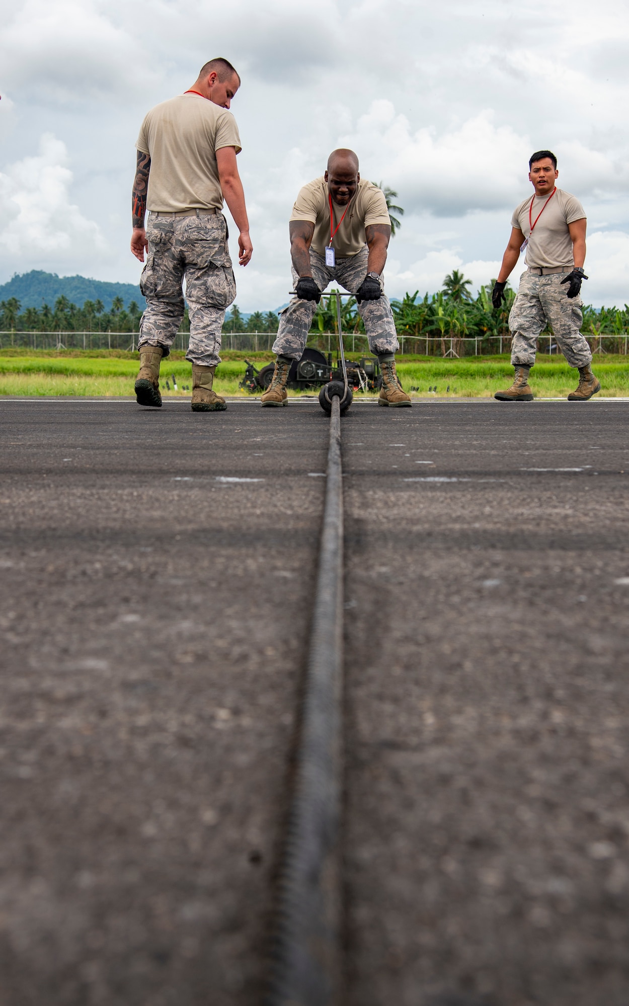 U.S. Air Force Tech. Sgt. DeMarco Poole, a 35th Civil Engineer Squadron electrical system craftsman from Misawa Air Base, Japan, spaces out the rollers on the mobile aircraft arresting system (MAAS) cable at the Sam Ratulangi International Airport, Manado, Indonesia, June 17, 2019. The small rollers keep the cable up off the runway so the hook can grab it. Six MAAS technicians forward deployed to Indonesia to support Cope West 19.The MAAS is designed to ensure pilots land and take-off safely in the event of an in-flight emergency. (U.S. Air Force photo by Staff Sgt. Melanie A. Hutto)