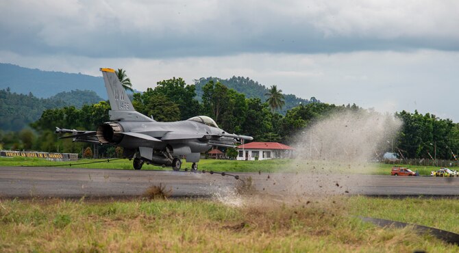 A U.S. Air Force F-16 Fighting Falcon from the 14 Fighter Squadron, Misawa Air Base, Japan,  pulls the mobile aircraft arresting system (MAAS) cable at the Sam Ratulangi International Airport, Manado, Indonesia, June 17, 2019. The MAAS is a contingency airfield asset that allows for the safe retrieval of tail hook aircraft during an in-flight emergency. It is air-portable and can be installed in a variety of methods and on practically any surface type to provide coverage in a variety of scenarios. (U.S. Air Force photo by Staff Sgt. Melanie A. Hutto)