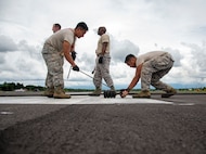 U.S. Air Force Airmen from the 35th Civil Engineer Squadron from Misawa Air Base, Japan, space out the rollers on a mobile aircraft arresting system (MAAS) cable at the Sam Ratulangi International Airport, Manado, Indonesia, June 17, 2019. The small rollers keep the cable up off the runway so the hook can grab it. Six MAAS technicians forward deployed to Indonesia in support of Cope West 19.The MAAS is designed to ensure pilots land and take-off safely in the event of an in-flight emergency. (U.S. Air Force photo by Staff Sgt. Melanie A. Hutto)