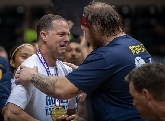 Navy Petty Officer 1st Class Tyson Schmidt, right, gives Navy Capt. Daryl Schaffer, left, his gold medal for sitting volleyball during the 2019 DoD Warrior Games at Yuengling Center in Tampa, Florida