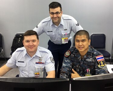 Tech. Sgt. Brandon Whitley and Airmen 1st Class Matt Laroche pose for a photo with their Royal Thai Air Force counterpart during the first-ever cyberspace field training exercise as part of Exercise Cobra Gold in Bangkok, Kingdom of Thailand, Feb. 12, 2019.