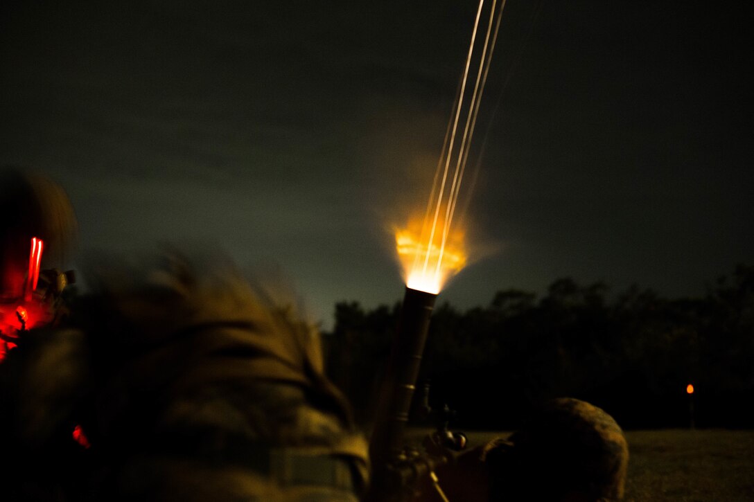 Marines fire a mortar round into the night sky.