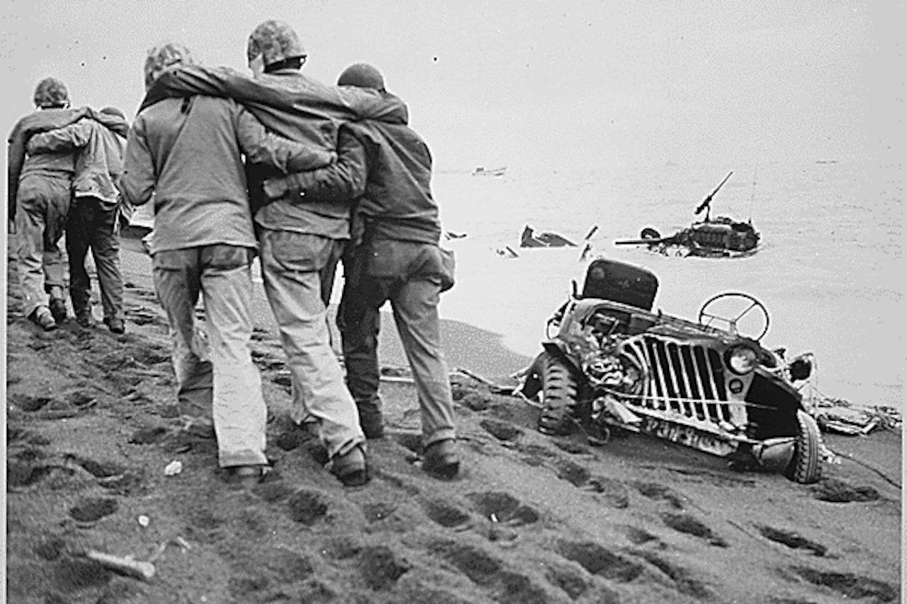 Men walk on a beach as a destroy Jeep sinks into sand.
