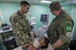 Lt. John Sullivan conducts thyroid ultrasound training with Brazilian navy Cmdr. Carlos Marsico aboard Brazilian navy hospital ship NAsH Carlos Chagas (U 19) off the coast of Prainha, Brazil during a medical clinic, Feb. 26.