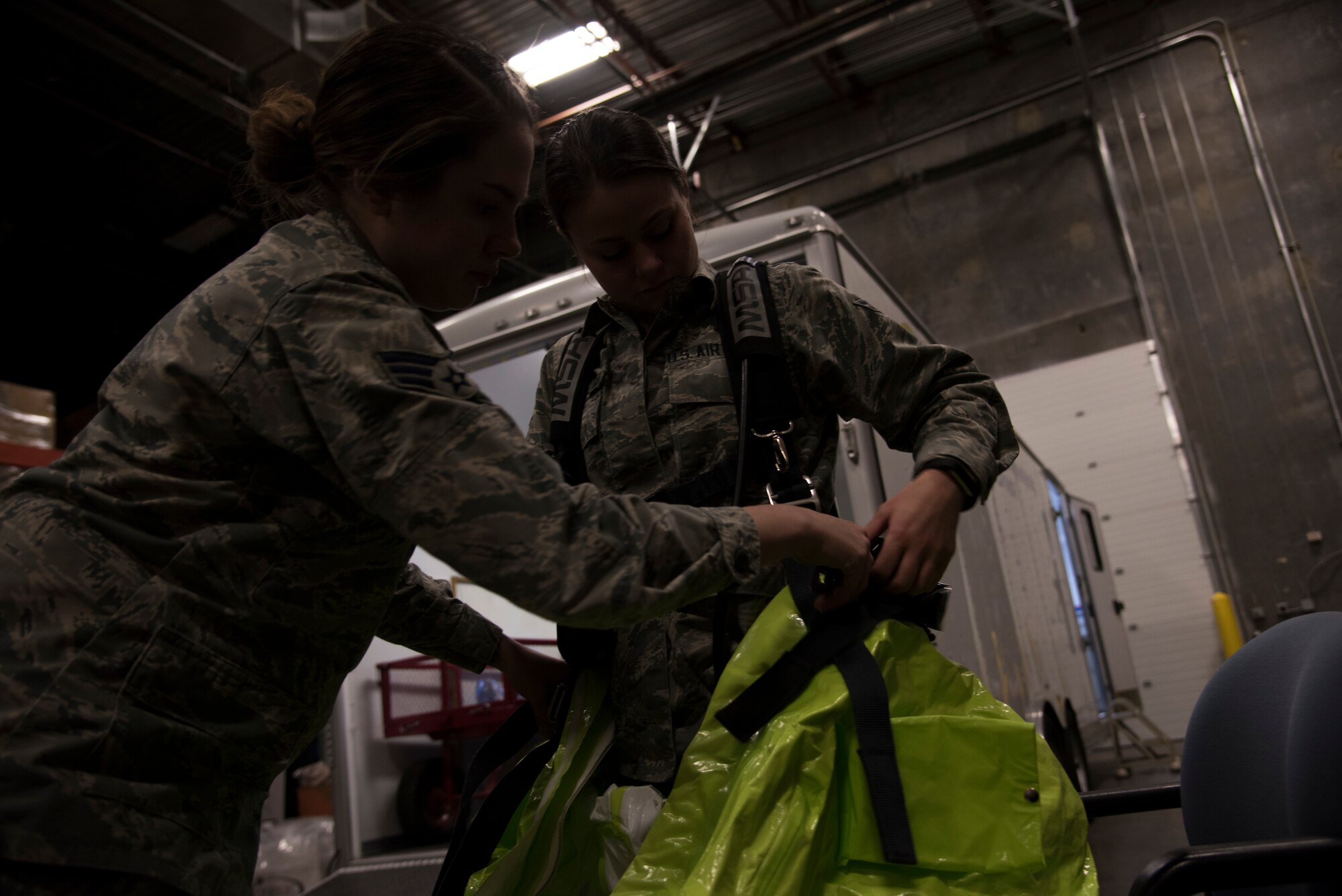 Senior Airman Katelynn Rosario assits Airman First Class Amanda Mathes-Orr dons a bioenvironmental hazard suit, Feb 27, 2019 at Mountain Home Air Force Base, Idaho.  Suits like the one shown, are designed to protect against many different types of hazards. (U.S. Air Force photo taken by Airman Nicholas Swift)