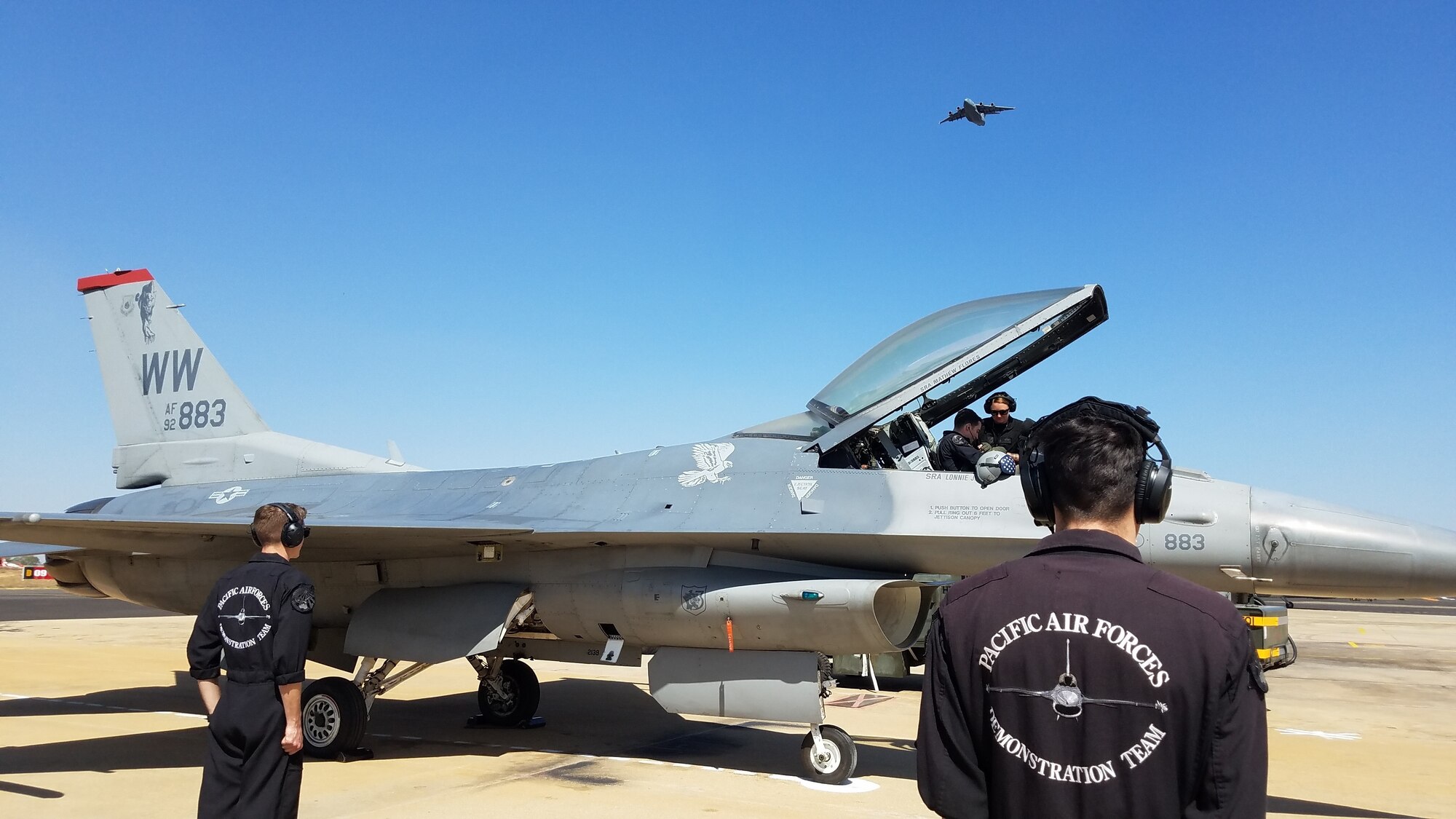 A U.S. Air Force C-17 Globemaster III, assigned to the 535th Airlift Squadron, Joint Base Pearl Harbor-Hickam, Hawaii, flies over as Pacific Air Forces’ F-16 Demonstration Team members, Misawa Air Base, Japan, finish their final checks before marshalling the jet for take off during Aero India 2019, at Air Force Station Yelahanka, Bengaluru, India, Feb. 23, 2019.