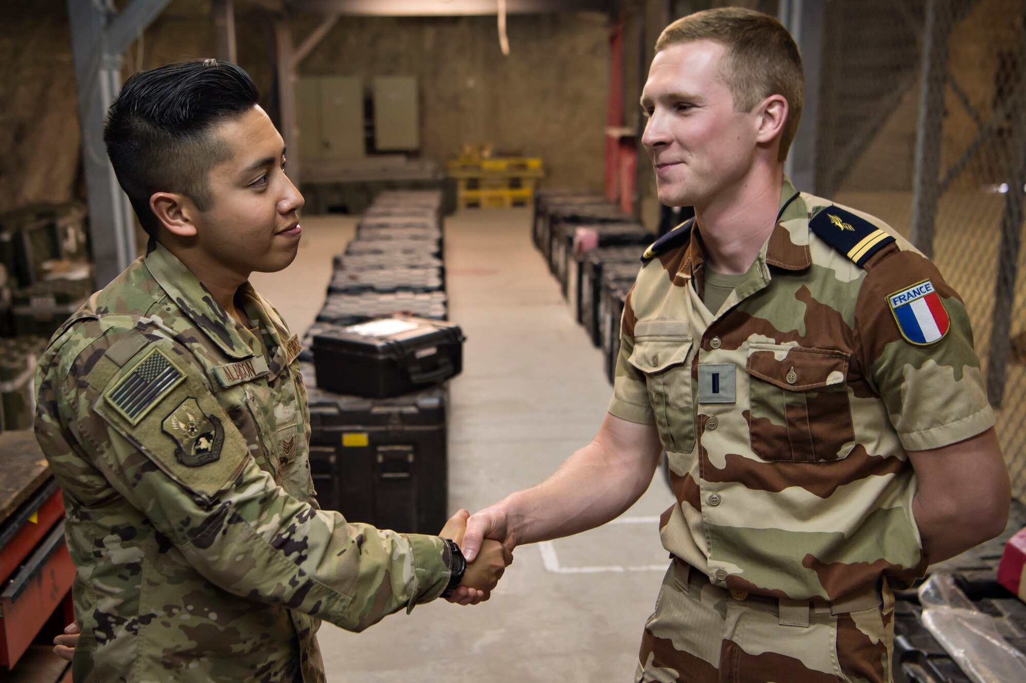 Staff Sgt. Aldrin Alarcon, 379th Expeditionary Communications Squadron (ECS) plans and requirements manager, shakes hands with French Air Force 1st Lt. Simon, engineering officer, after installating communication assets for a French Air Force detachment facility Feb. 26, 2019, at Al Udeid Air Base, Qatar. Alarcon is part of a “beddown” team that enables power projection by establishing communications capabilities such as networks, Voice over Internet Protocol telephones, and radios from the ground up (U.S. Air Force photo by Tech. Sgt. Christopher Hubenthal)