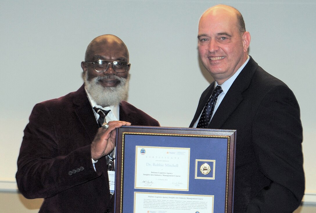 Robbie Mitchell, a supply systems analyst in DLA Logistics Operations, receives his certificate for completing the Insights into Industry Course from DLA Acquisition Director Matthew Beebe.