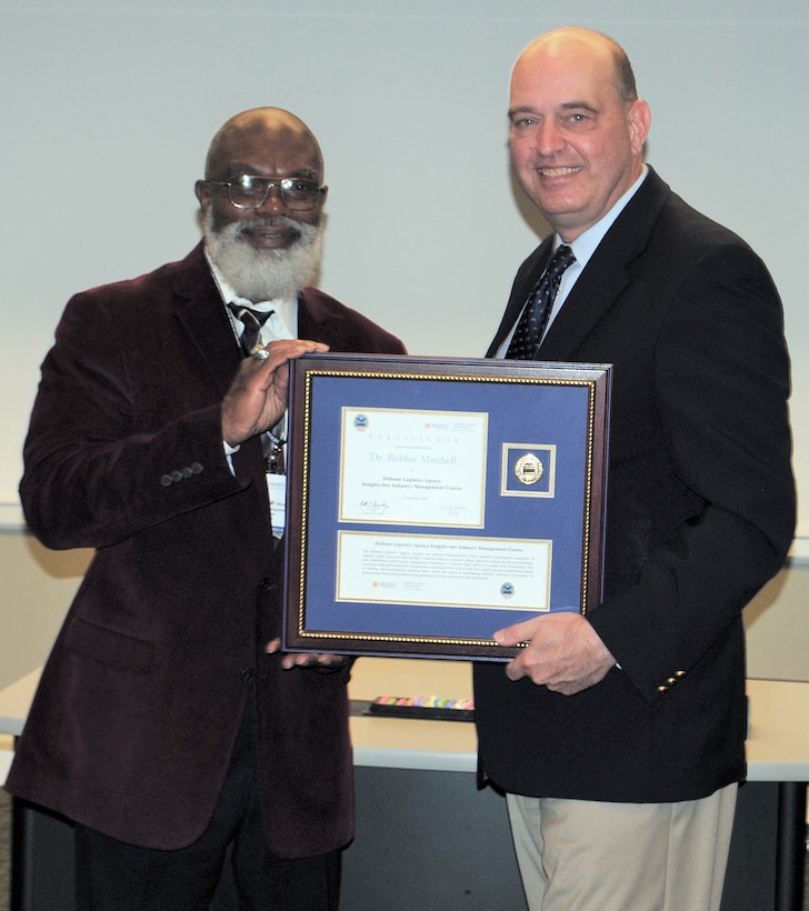 Robbie Mitchell, a supply systems analyst in DLA Logistics Operations, receives his certificate for completing the Insights into Industry Course from DLA Acquisition Director Matthew Beebe.