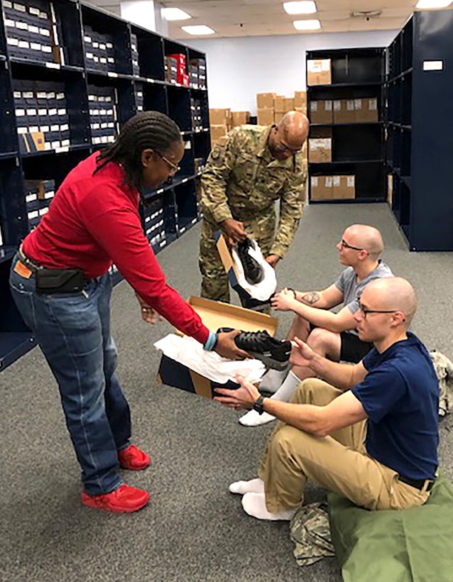 Vernalynne Carter, chief of clothing initial issue for the Air Force, and 502nd Logistics Readiness Squadron Commander Air Force Lt. Col. Ernest Cage issue new American-made athletic footwear to recruits Daniel Sterling (bottom right) and Ryan Padro (top right) at Joint Base San Antonio-Lackland, Texas, in January.