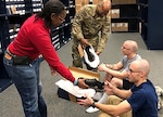 Vernalynne Carter, chief of clothing initial issue for the Air Force, and 502nd Logistics Readiness Squadron Commander Air Force Lt. Col. Ernest Cage issue new American-made athletic footwear to recruits Daniel Sterling (bottom right) and Ryan Padro (top right) at Joint Base San Antonio-Lackland, Texas, in January.
