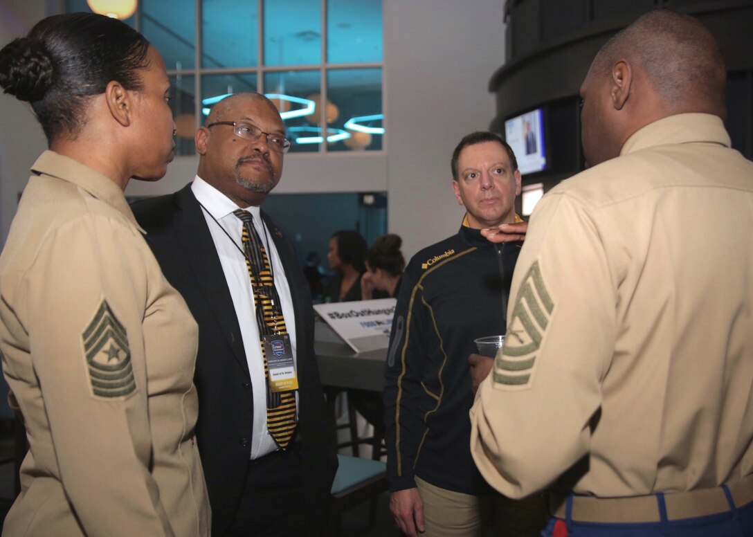 Sgt. Maj. Robin Fortner (left), Artie Travis, Anthony Savia and Master Sgt. Damian Cason speak together at the Central Intercollegiate Athletic Association President’s Reception, during the CIAA 2019 basketball tournament at Spectrum Center in Charlotte, North Carolina, March 1, 2019. The Marine Corps Recruiting Command (MCRC) partners with organizations like CIAA to improve diversity representation within the Marine Corp’s leadership ranks and to re-invigorate connectedness with the American people. The CIAA annual basketball tournament is one of the nation’s premier sporting events, attracting over 190,000 fans over the course of the week. Fortner is the Marine Corps Systems Command sergeant major. Travis is the vice president of student affairs at Bowie State University in Bowie, Maryland. Savia is the vice president for administration and finance at Bowie State University. Cason is the community engagement chief for MCRC. (Marine photo by Cpl. Naomi May)