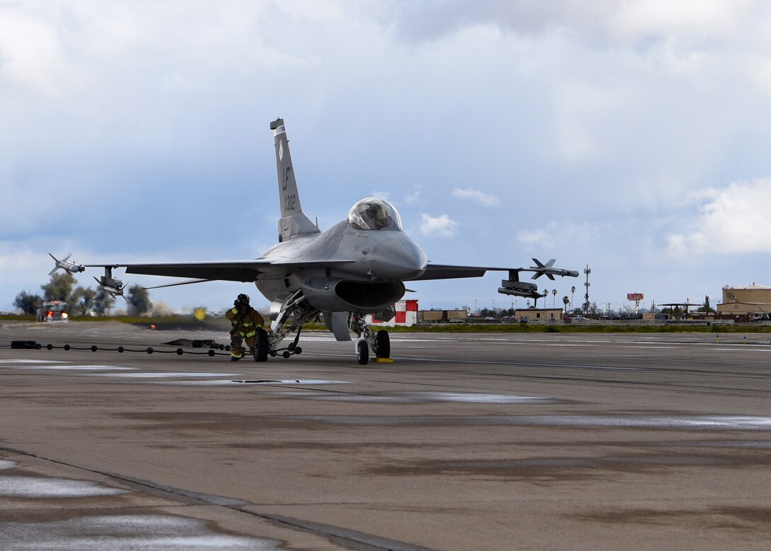 An airman from the 56th Civil Engineer Squadron prepares to release an F-16A Fighting Falcon from a BAK-12 arresting system at Luke Air Force Base, Ariz., Feb. 22, 2019.