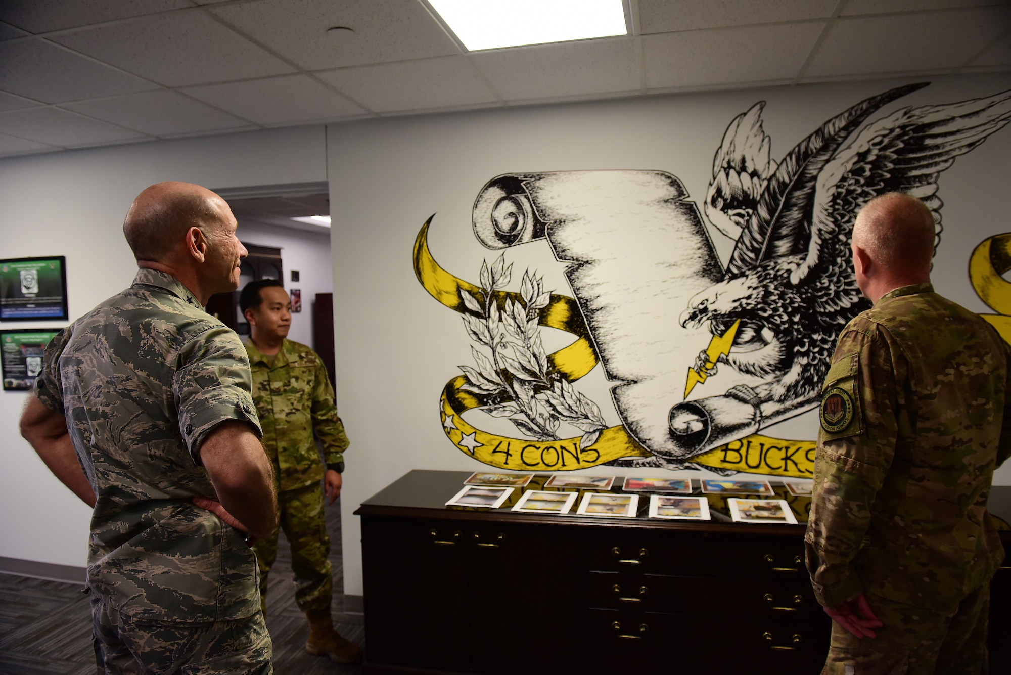 Gen. Mike Holmes, commander of Air Combat Command, left, and Chief Master Sgt. Frank Batten, command chief of ACC, right, view a mural drawn by Senior Airman Benedick Duria, 4th Contracting Squadron contract specialist (center), Feb. 26, 2019, at Seymour Johnson Air Force Base, North Carolina. Duria hand sketched the mural and colored it using paint and permanent markers. (U.S. Air Force photo by Senior Airman Kenneth Boyton)