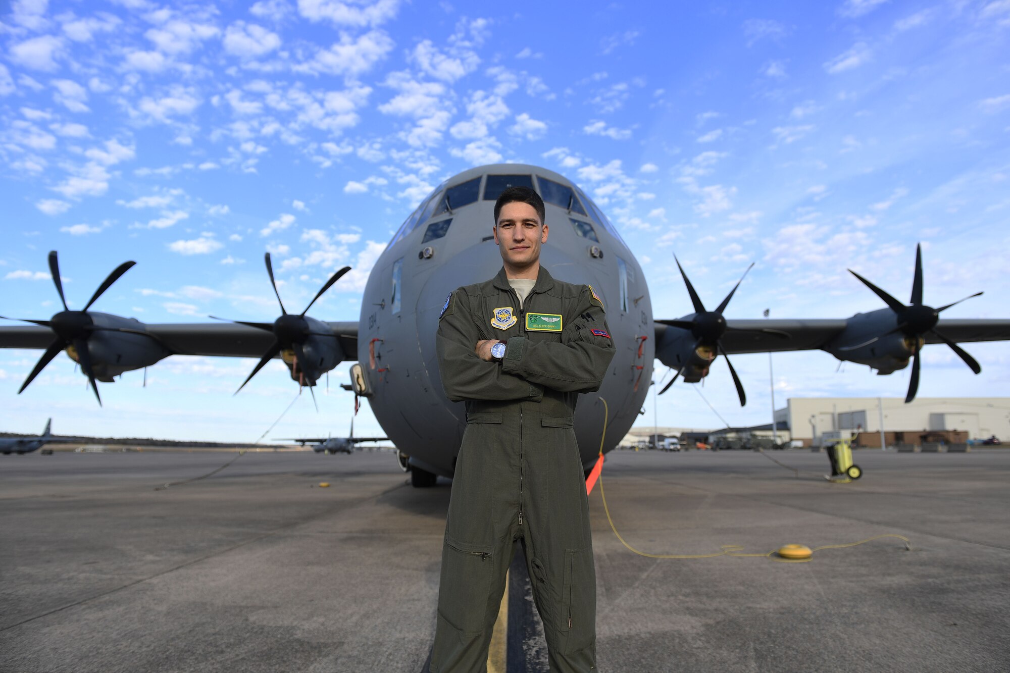 Airman stands with arms crossed in front of C-130J.