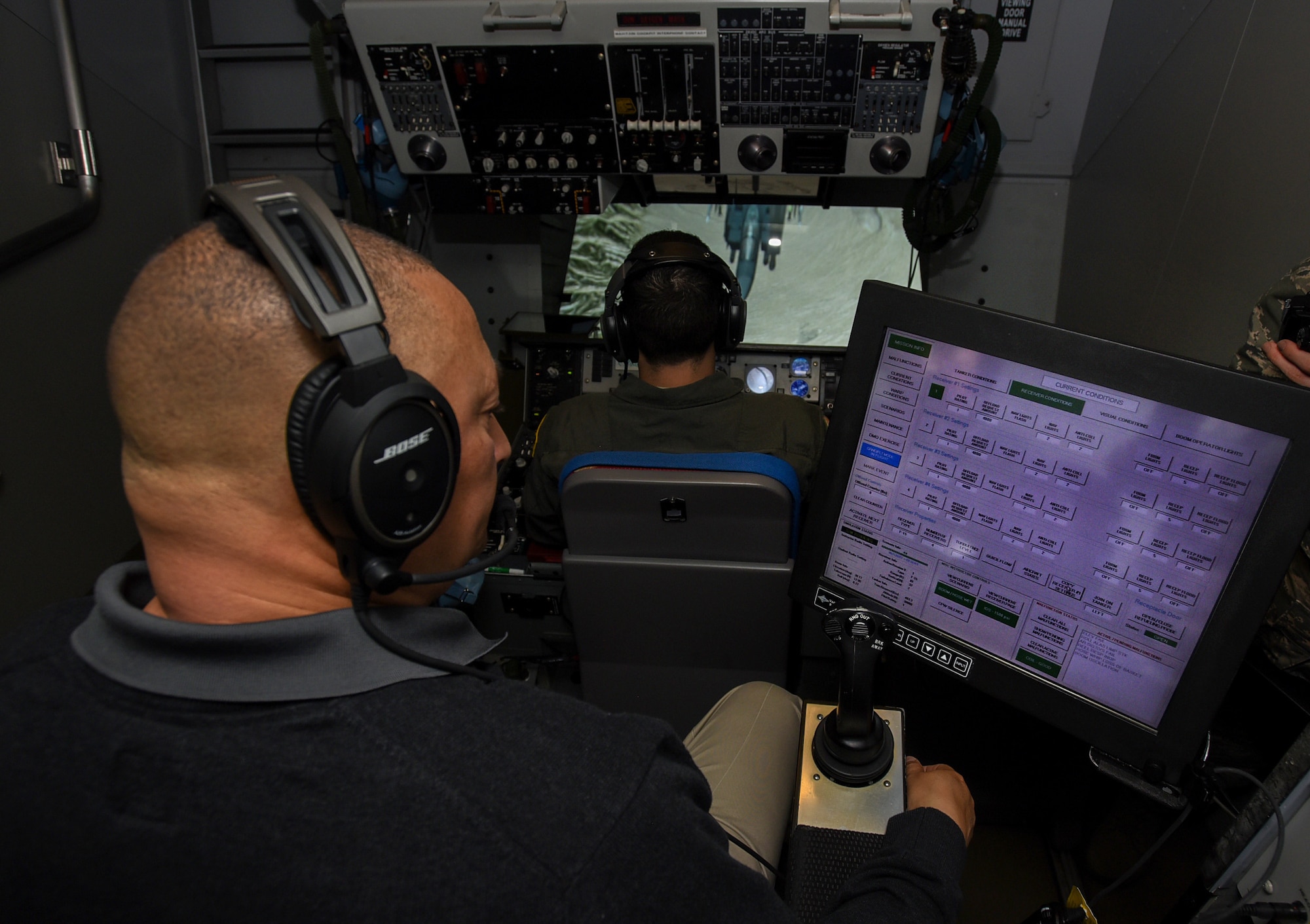 Steven Custis, KC-10 Extender boom operator instructor, oversees Airman 1st Class Nicholas Eddings, 32nd Air Refueling Squadron KC-10 boom operator, during a simulated refueling mission on Joint Base McGuire-Dix-Lakehurst, New Jersey, Dec. 19, 2018. Crewmembers train in simulators that include a hydraulics system that mimics the sensation of an aircraft. (U.S. Air Force photo by Airman 1st Class Ariel Owings)