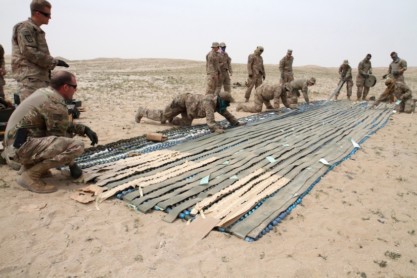 Soldiers from Task Force Spartan and Airmen from the 407th and 386th Expeditionary Civil Engineer Squadrons work together to apply sheet explosives to 40 mm ammunition so it can be disposed of during a controlled detonation on the Udairi Range, Kuwait, Feb. 27, 2019. Properly disposing of unserviceable ammunition, like these 40 mm rounds, allows local ammunition holding areas to store more ammunition that can be used in local training events or other contingencies as they arise.