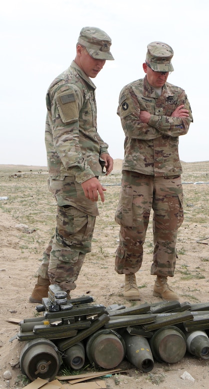 Brigadier Gen. Charles Kemper, deputy commanding general for support, 34th Red Bull Infantry Division, Task Force Spartan, speaks with Sgt. Gabriel Leon, 705th Explosive Ordnance Disposal Company, Task Force Hellhound, Task Force Spartan, about the ordnance included in this shot pit prior to a controlled detonation of more than 6,800 pounds of unserviceable ammunition on the Udairi Range, Kuwait, Feb. 27, 2019. Kemper assisted in priming the charges for the four separate shot pits.