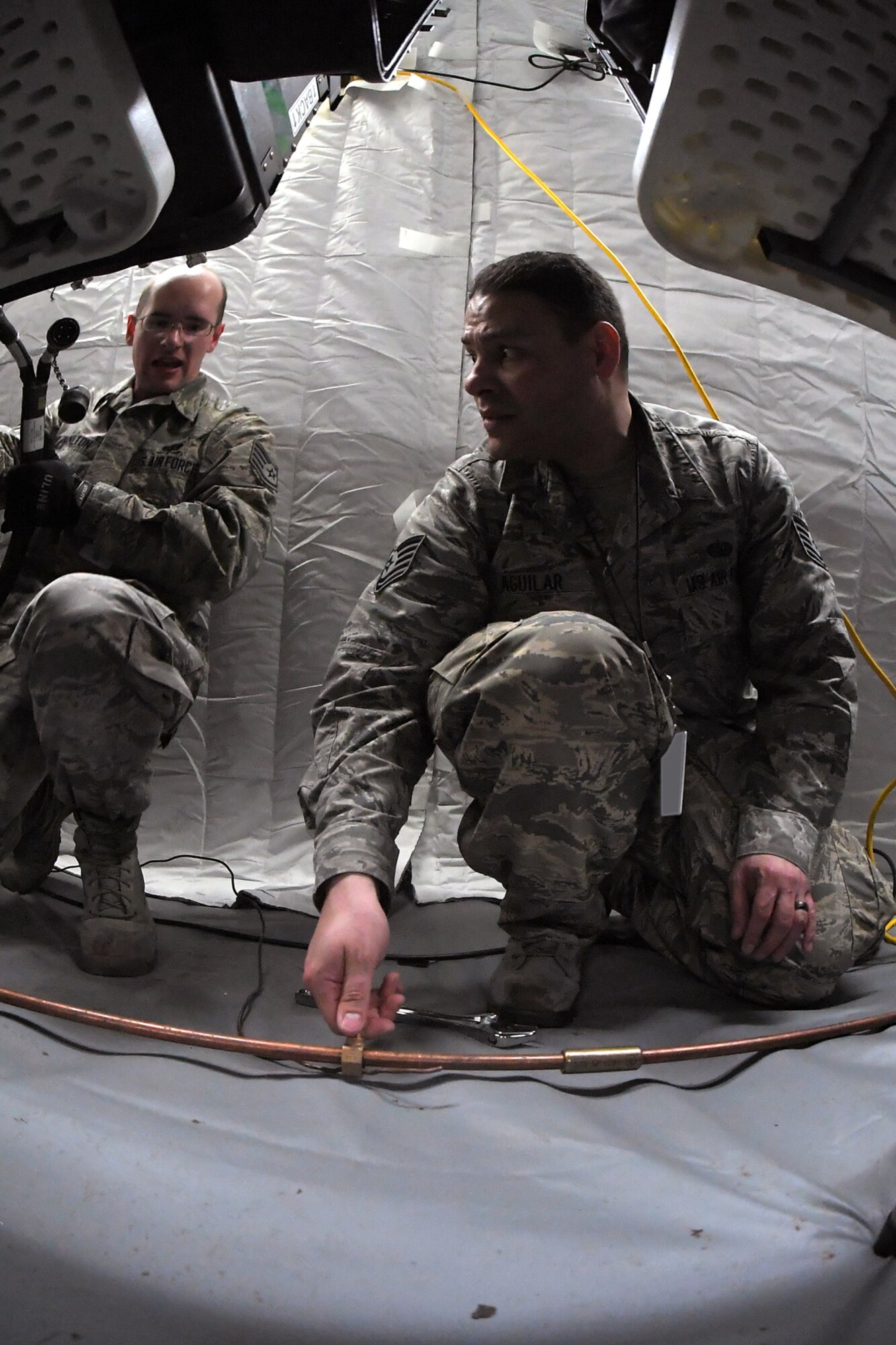 Technical Sgt. Kevin Aguilar (center) and Staff Sgt. Joshua Hamilton, both 729th Air Control Squadron, hook up an equipment grounding wire Feb. 5, 2019, during a readiness exercise at Hill Air Force Base, Utah. The evolution was part of an exercise to mobilize and set up a deployed radar location and control reporting center. (U.S. Air Force photo by Todd Cromar)