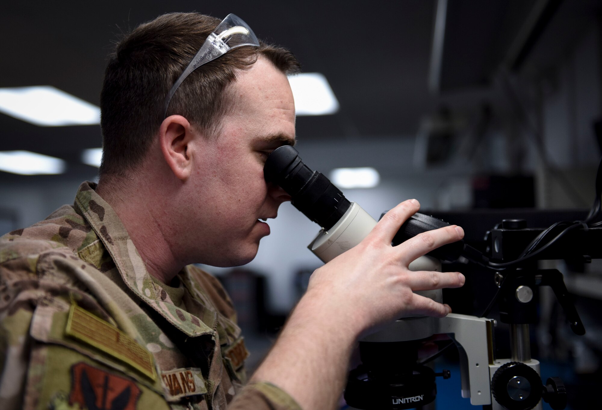 An Airman looks into a microscope.