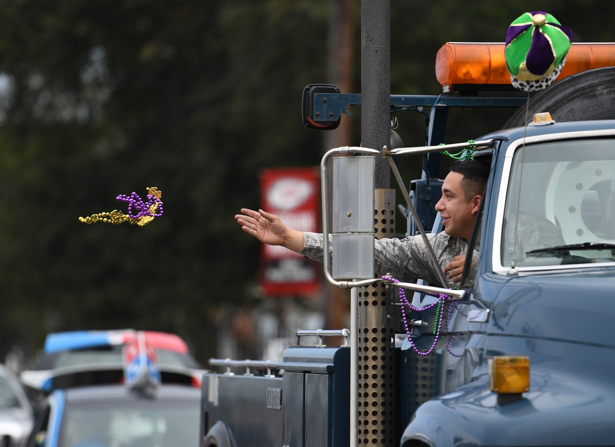 U.S. Air Force Senior Airman Andrew Hernandez, 81st Logistics Readiness Squadron training and validation, tosses beads to children during the Jeff Davis Elementary School Mardi Gras parade in Biloxi, Mississippi, March 1, 2019. Keesler leadership, Honor Guard and Airmen participated in various festivities throughout the Mardi Gras season, which is celebrated by the local communities. (U.S. Air Force photo by Kemberly Groue)