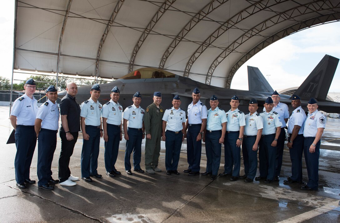 A group of U.S. and Philippine air force Airmen take a photo in front of an F-22 Raptor during a tour at Joint Base Pearl Harbor-Hickam, Hawaii, Feb. 25, 2019.