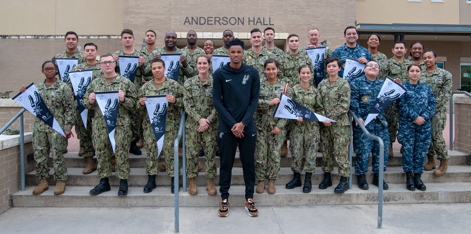 Dejounte Murray, San Antonio Spurs player No. 5, poses for a photo with Sailors assigned to Navy Medicine Training Support Center. Murray's visit was organized ahead of the Spurs' Navy-themed Military Salute Night.