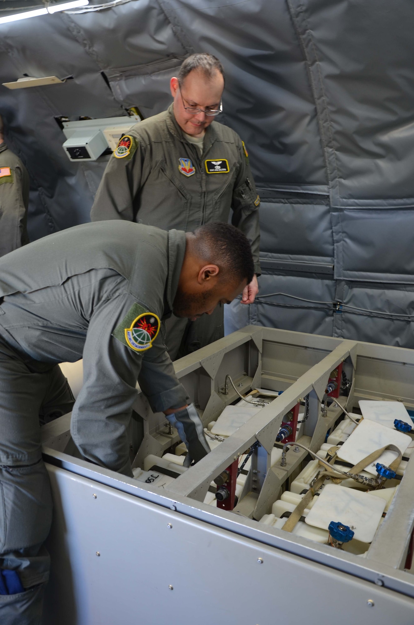 U.S. Air Force Senior Airman Victor Williams (front) repositions a whole air sphere aboard the WC-135 Constant Phoenix as Master Sgt. Jose Gallegos observes.  The Airmen, both special equipment operators, are members of the Air Force Technical Applications Center's Detachment 1 based at Offutt AFB, Neb., and were at Patrick AFB, Fla., to offer tours of the nuclear treaty monitoring aircraft.  (U.S. Air Force photo by Susan A. Romano)
