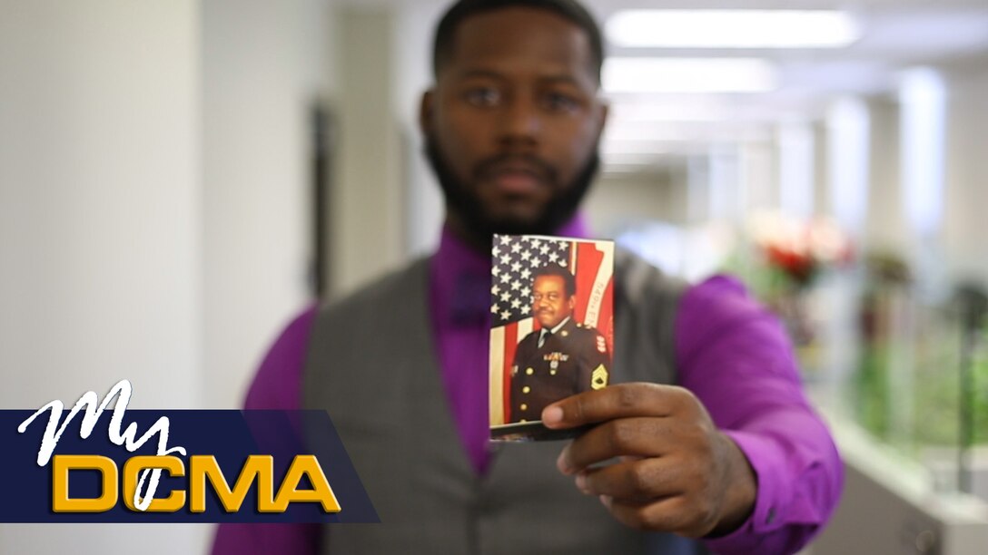 Man holds photo of another man in uniform.