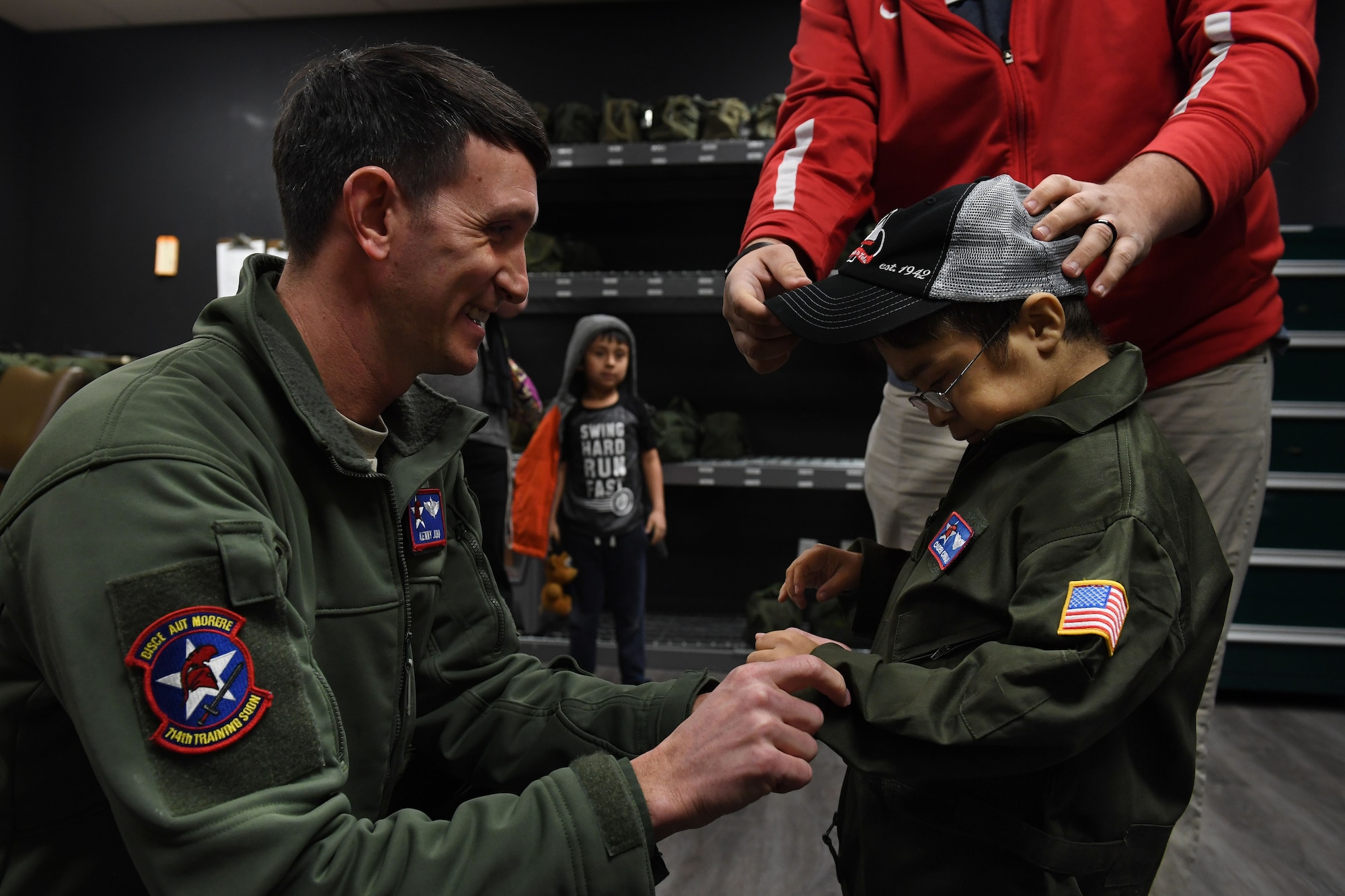 A pilot and helps zip up a jacket for a young boy