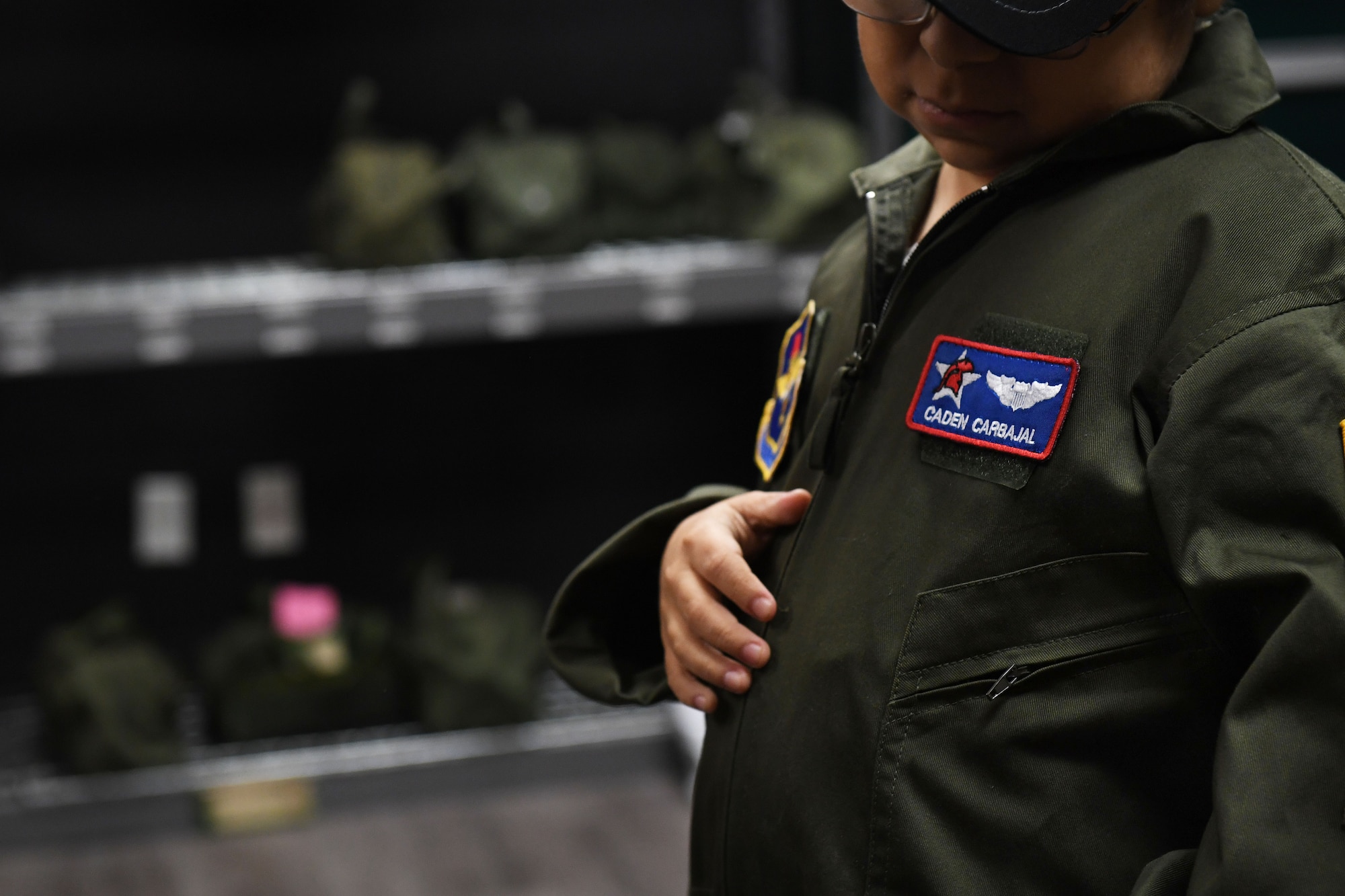 A young boy looks down at his name patch on his new flight suit