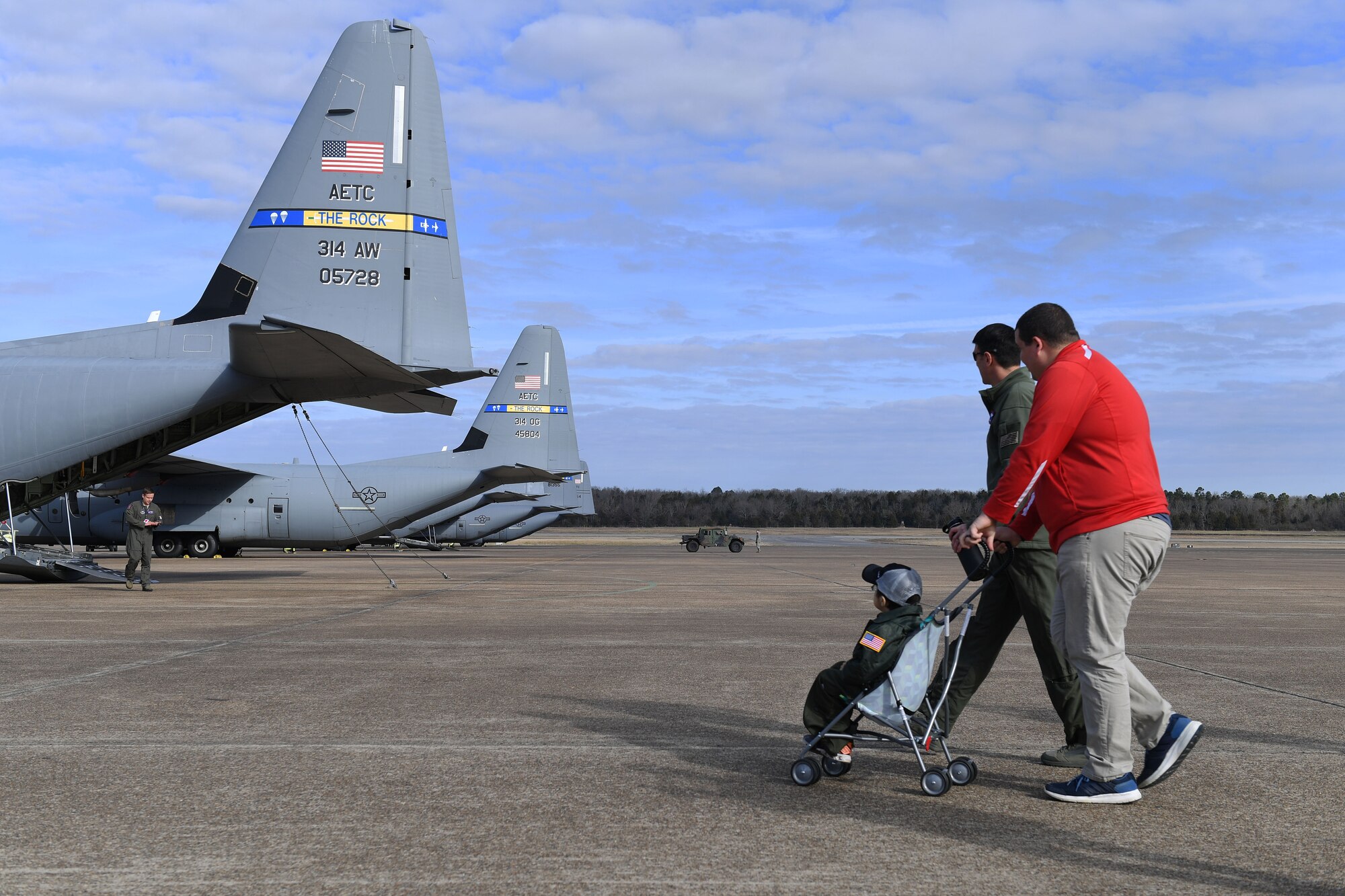a father pushed his son in a stroller to a C-130J on the flight line