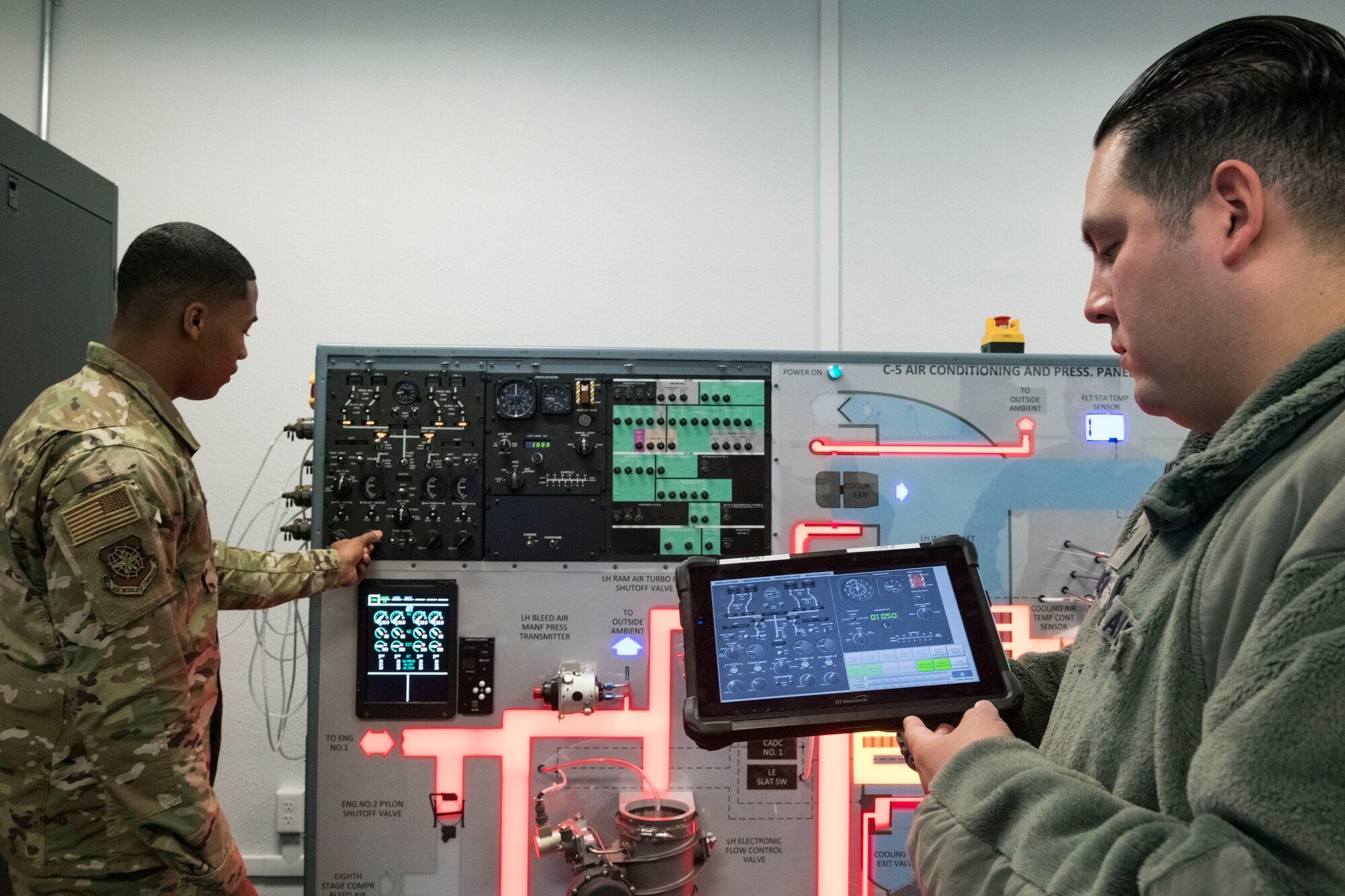 Aircraft Electrical and Environmental Systems journeyman Senior Airman Corey Wiggins, 437th Aircraft Maintenance Squadron, Joint Base Charleston, S.C., adjusts a temperature adjustment knob on the C-5 Air Conditioning and Pressurization Systems Trainer Feb. 20, 2019, at the 373rd Training Squadron, Detachment 3, on Dover Air Force Base, Del. The AC & PST visually allowed Wiggins and other students to see what occurs when switches are moved on the flight engineer’s control panel. On the right, Staff Sgt. Jose Cardona, 373rd TRS, Det 3, C-5M Electrical and Environmental Systems instructor, monitored knob movement initiated by Wiggins on the Interactive Multimedia Instruction tablet.(U.S. Air Force photo by Roland Balik)