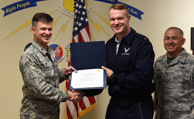 U.S. Air Force Col. Thomas Coakley, 17th Training Group commander, presents the 315th Training Squadron Officer Student of the Month award to 2nd Lt. Justin Campbell, 315th TRS student, at Brandenburg Hall on Goodfellow Air Force Base, Texas, March 1, 2019. The 315th TRS’s vision is to develop combat-ready intelligence, surveillance and reconnaissance professionals and promote an innovative squadron culture and identity unmatched across the U.S. Air Force. (U.S. Air Force photo by Airman 1st Class Abbey Rieves/Released)