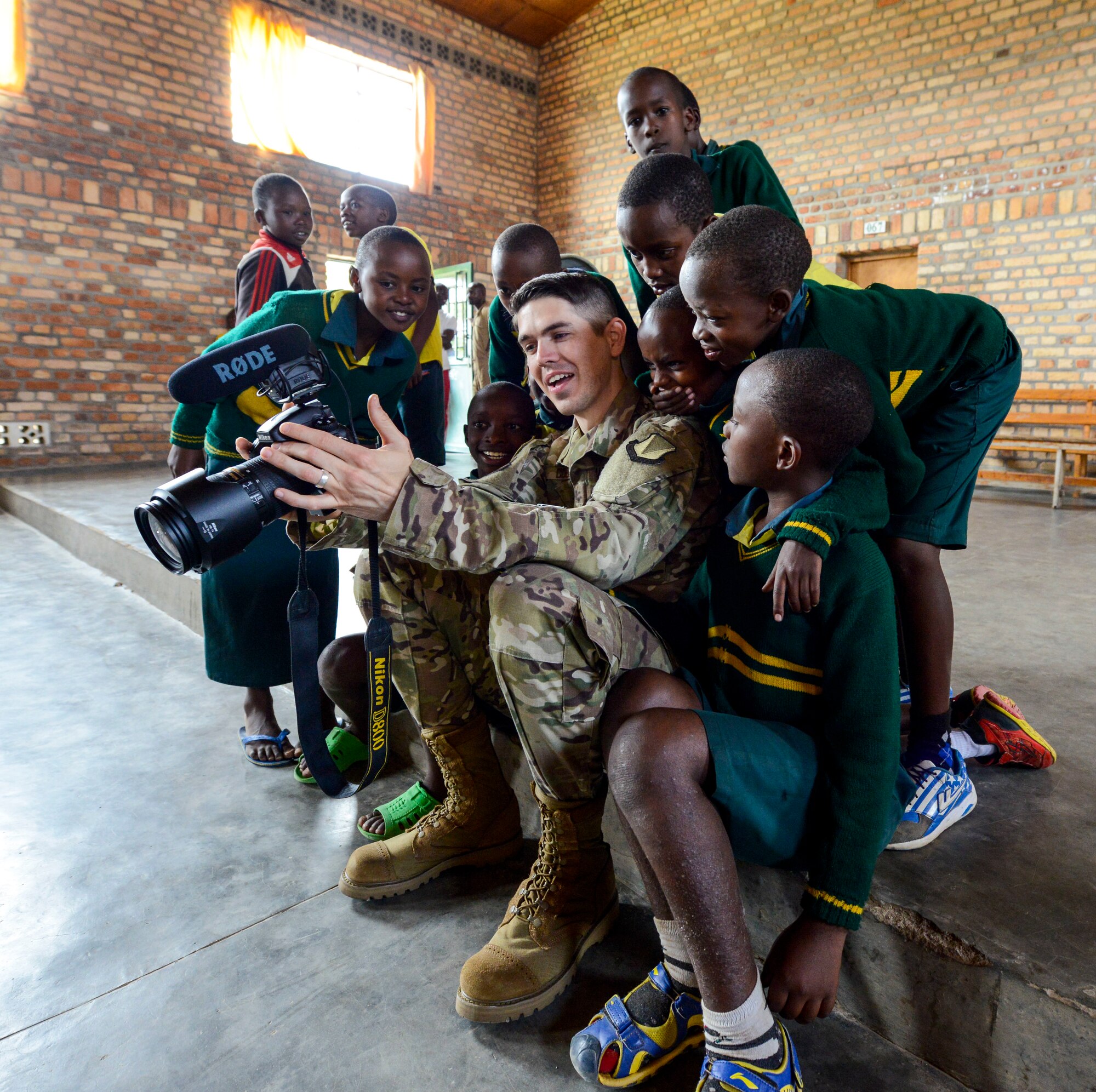 U.S. Air Force Airman 1st Class Noah Coger, 86th Airlift Wing Public Affairs broadcast journalist, shows video to some students of the Home de la vierge des Pauvres Gatagara/Nyanza in the Nyanza District, Rwanda, March 5, 2019. Coger traveled to HVP Nyanza with the U.S. Air Forces in Europe Band, who performed a musical concert for the students. (U.S. Air Forces photo by Tech. Sgt. Timothy Moore)